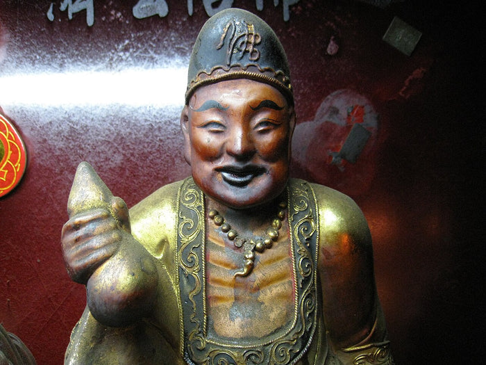 Ji Gong Huo Fo statue, laughing, with his tattered-monk look and holding a wine gourd.