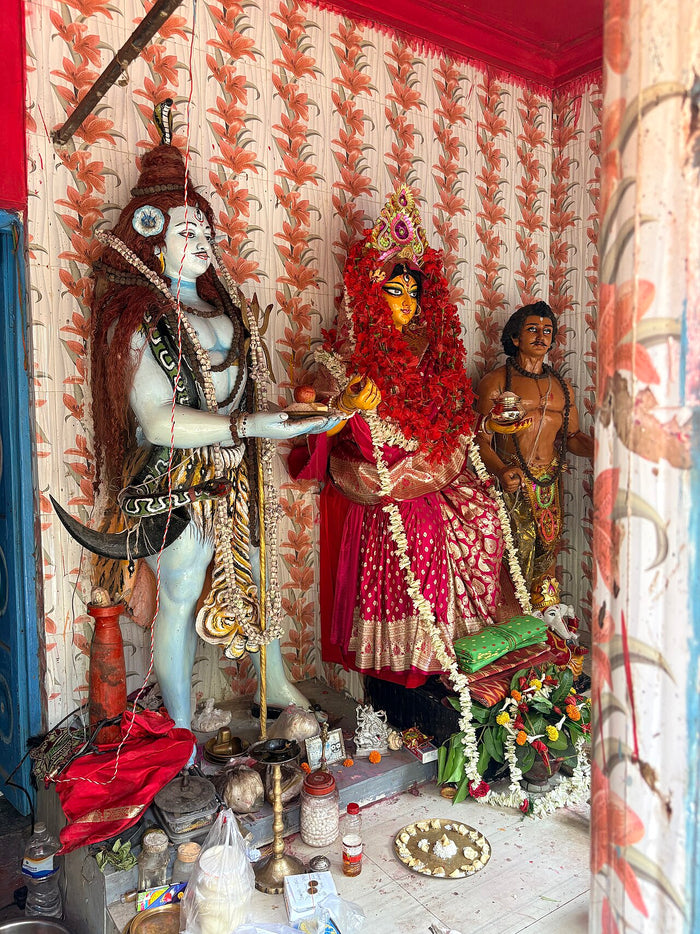 Annapurna Puja at Behala: goddess offering food to Shiva, who holds a trident, with another attendant figure beside them.