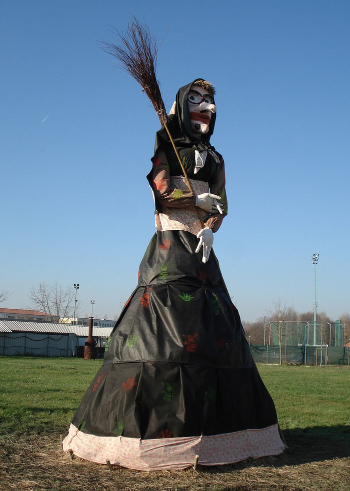 Large Befana effigy in black dress and headscarf holding a broom, as made for Epiphany celebrations.