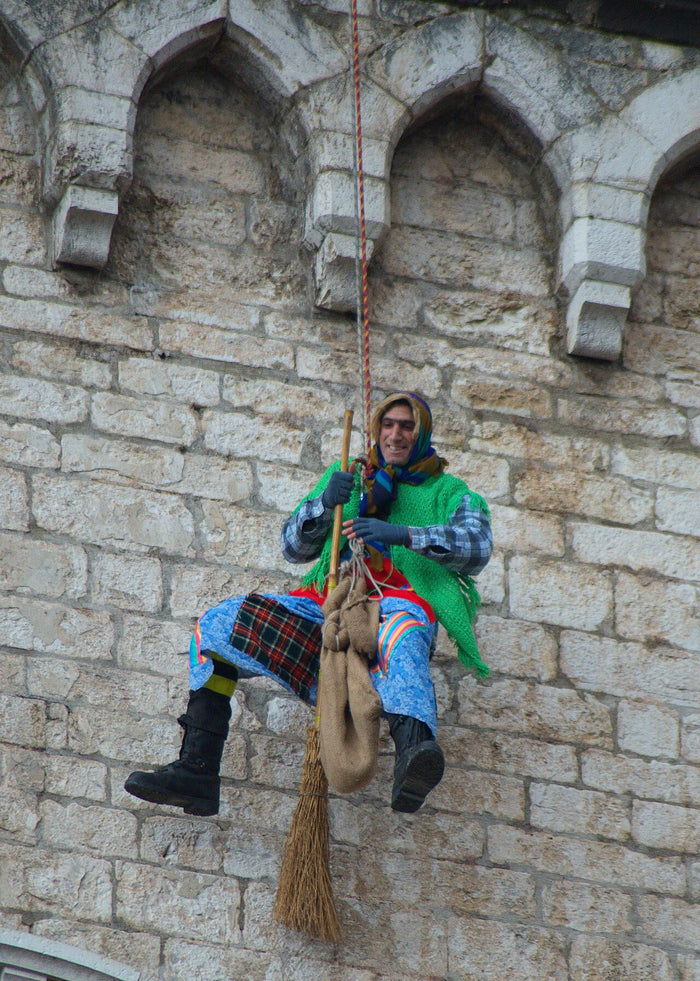 Befana figure with broom and sack lowered down a stone building on Epiphany, 6 January 2011.
