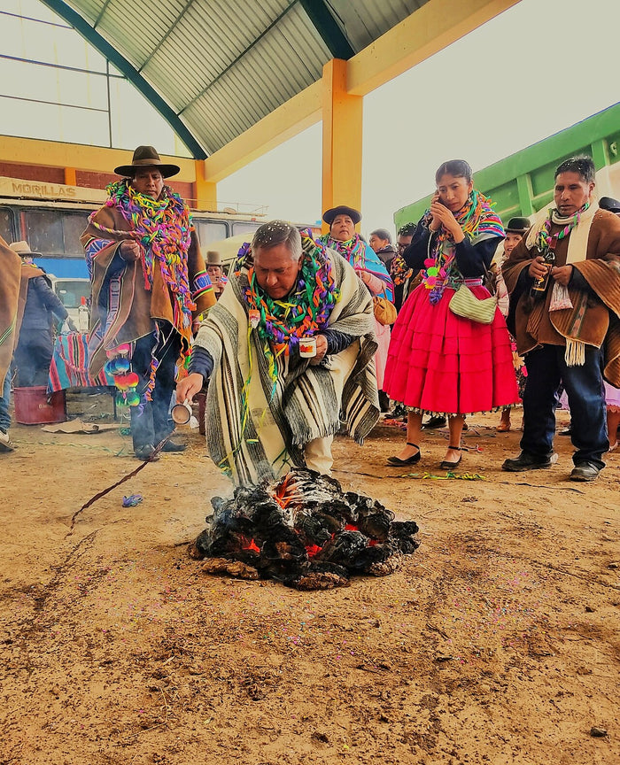 Challa to the earth during Ácora carnival, 2025: participants make libations beside a burning offering, a living Pachamama practice.