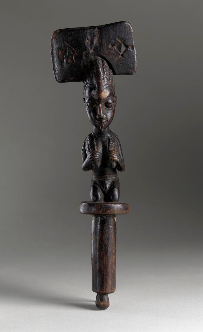 Yoruba dance wand for Shango devotees: a kneeling worshipper beneath the double-axe blade, symbol of Ṣàngó's thunder.