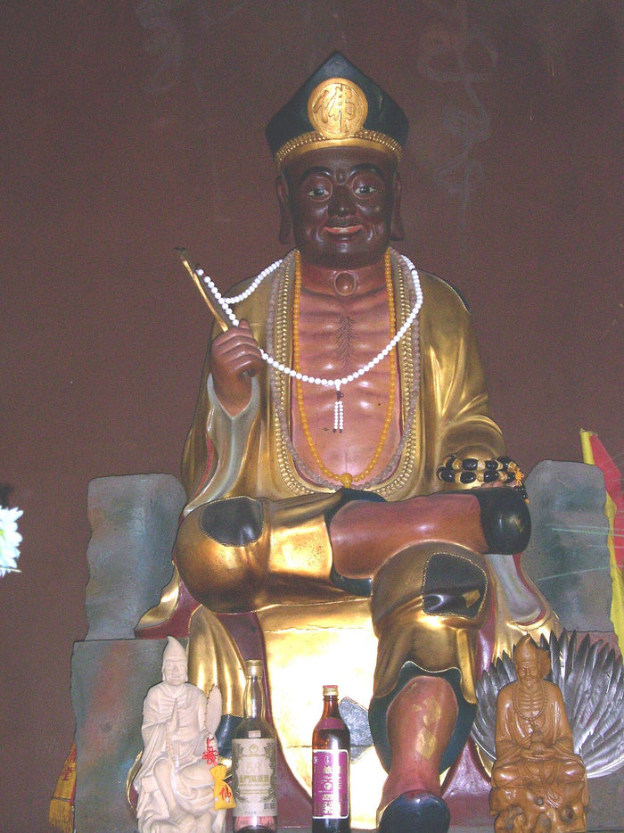 Gilded statue of Daoji (Ji Gong) at his temple, smiling with a fan and prayer beads.