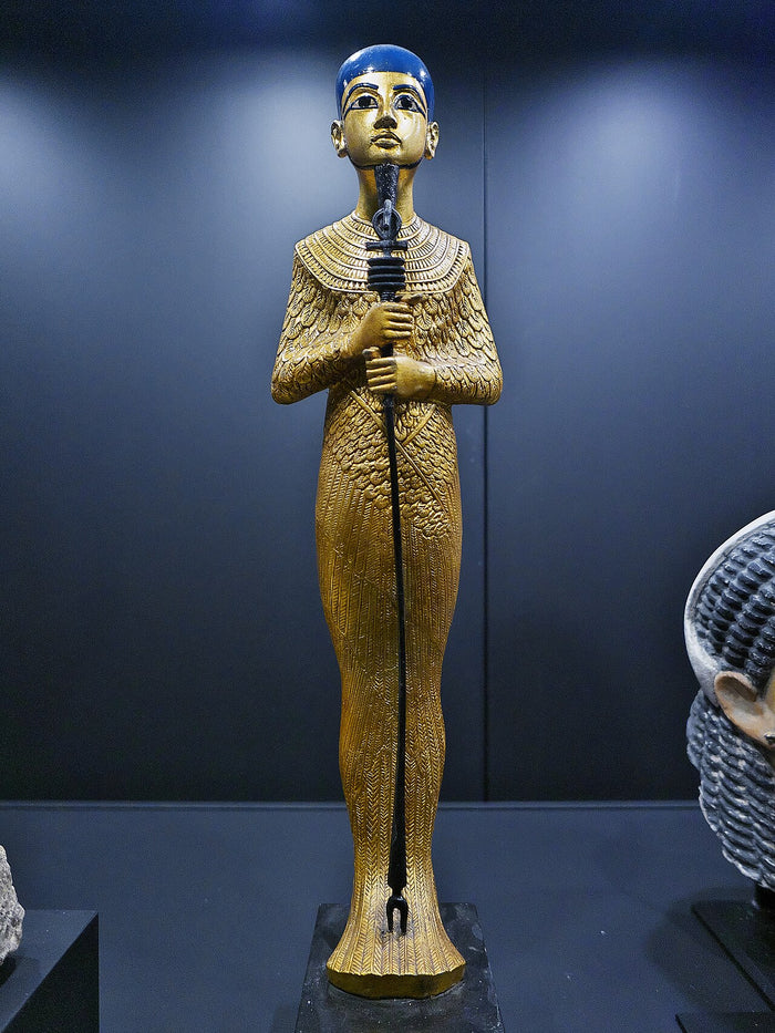 Gilded wooden Ptah from Tutankhamun's tomb, with blue skullcap and tight shroud, holding the combined djed, was and ankh sceptre.