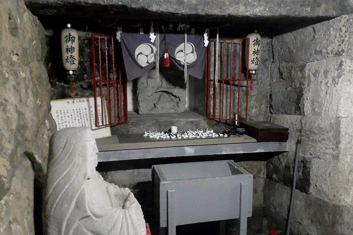 Cave shrine at Ejima Sugiyama Shrine, Tokyo, with a seated stone figure honouring Benzaiten, Saraswati's Japanese form.