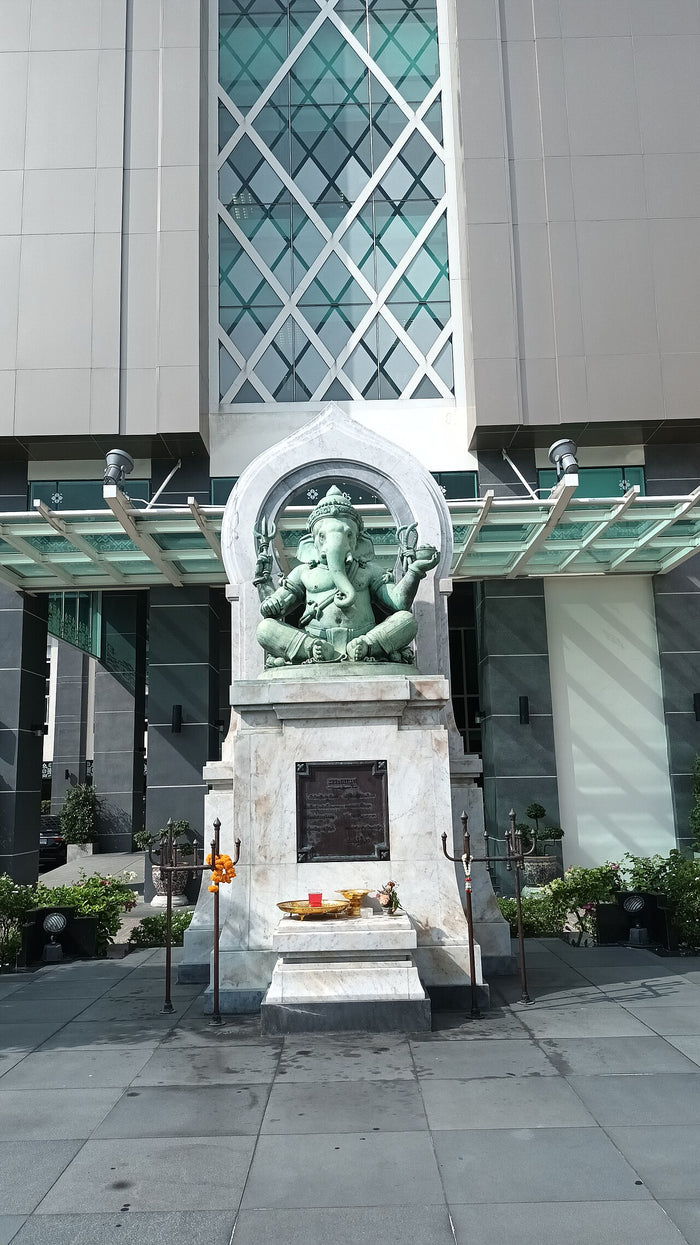 Green bronze Ganesha in an arched shrine outside a building in Bangkok, showing his reach beyond India.