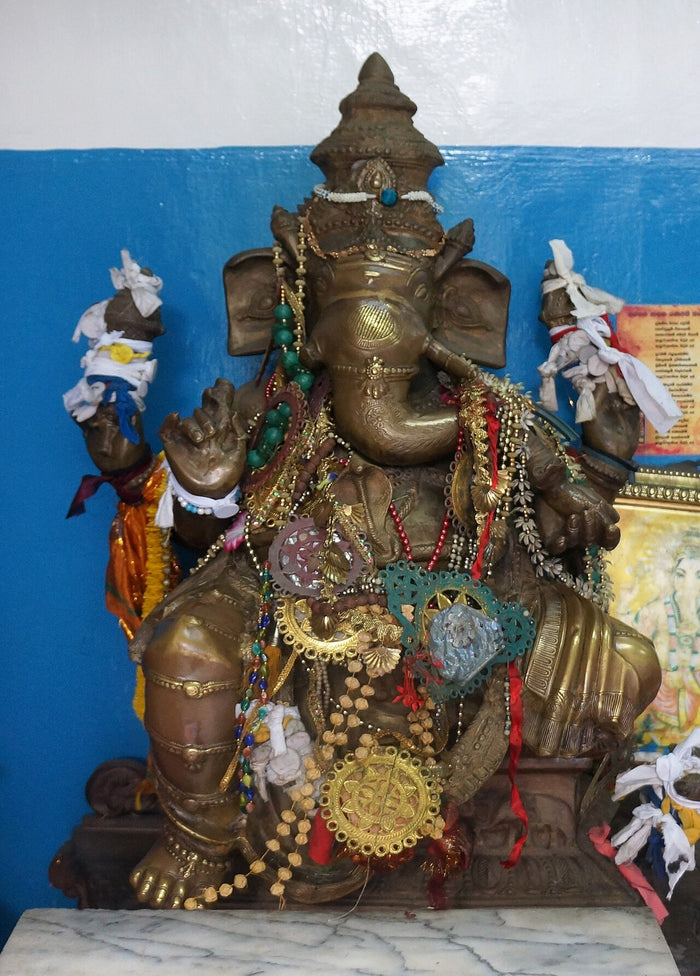 Bronze Ganesha adorned with beads and garlands, showing how devotees dress the deity in temple worship.