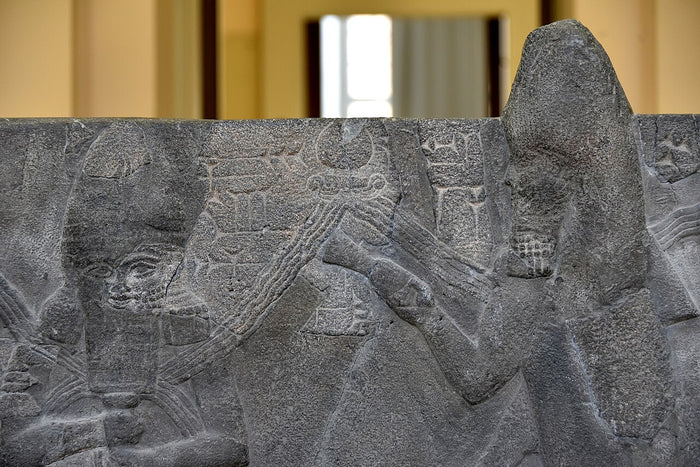 Ea with a fish-cloaked apkallu on the Assur basin from Sennacherib's reign, showing the god's link to wisdom and sages.