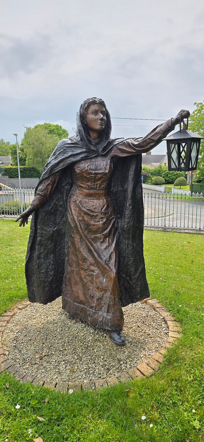 Bronze statue of Brigid of Kildare at Kildare, holding a lantern, the light-and-flame symbol linked to Brigid and Imbolc.