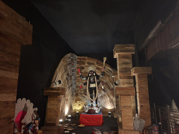 Kali Puja image, 2023: dark Kali with raised sword and long garland, standing over a reclining Shiva.