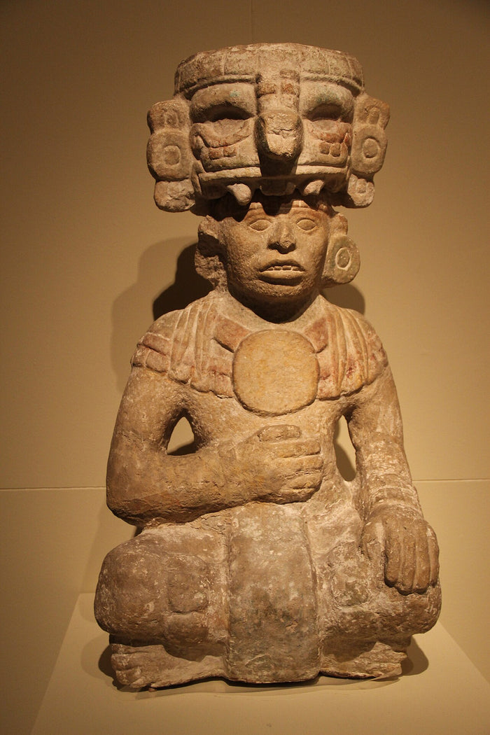 Seated man wearing a Chaak headdress from Chichen Itza, showing the god's mask used in ritual costume.