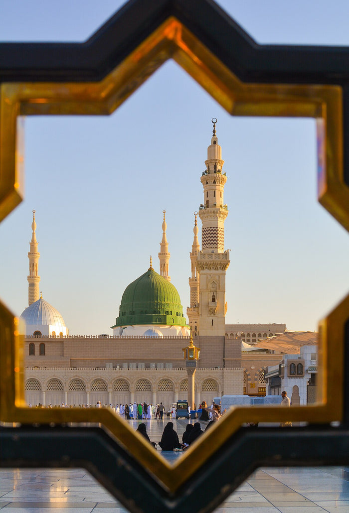 Green dome and minarets of the Prophet's Mosque in Medina, framed by a star-shaped lattice; Muhammad's tomb is here.