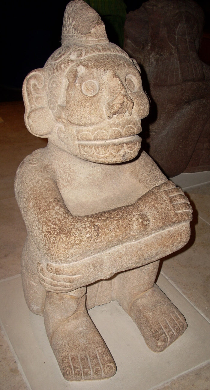 Seated stone Mictlantecuhtli at the British Museum, with a skull face, bared teeth and arms folded over the knees.