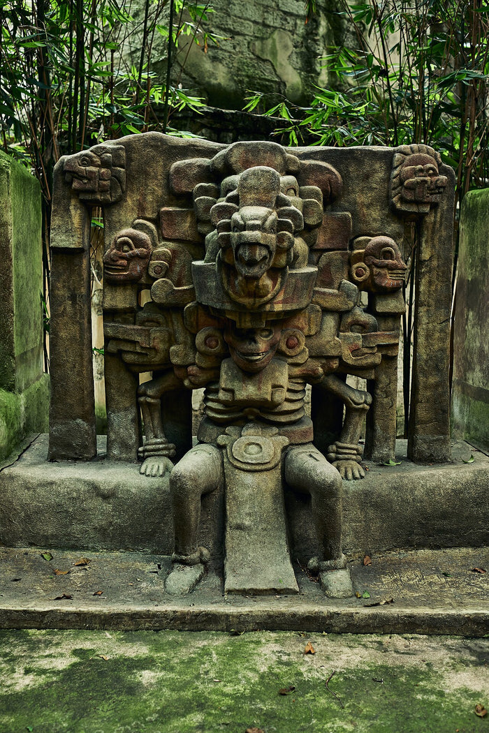Carved stone seated figure of Mictlantecuhtli with a skeletal body and elaborate headdress, framed by a throne-like relief, at the MNA.