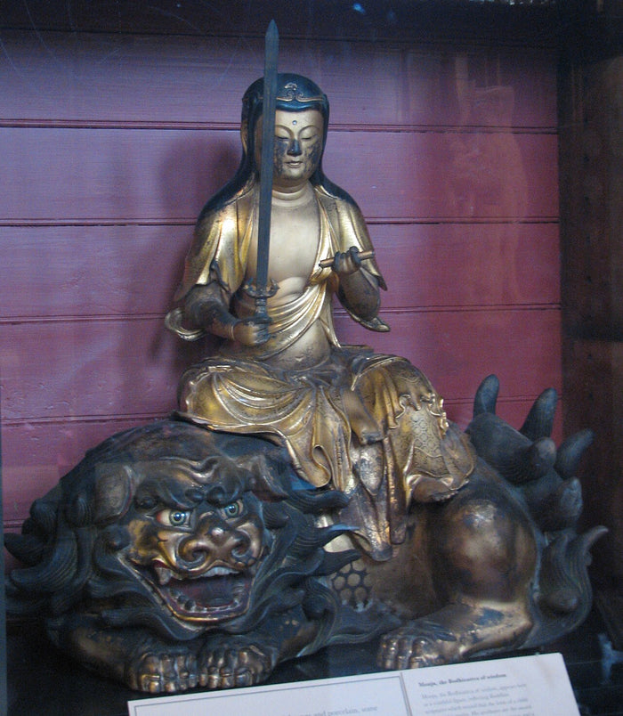 Gilt wooden Monju seated on a lion, holding a sword; British Museum. Shows his classic mount and attribute of wisdom.