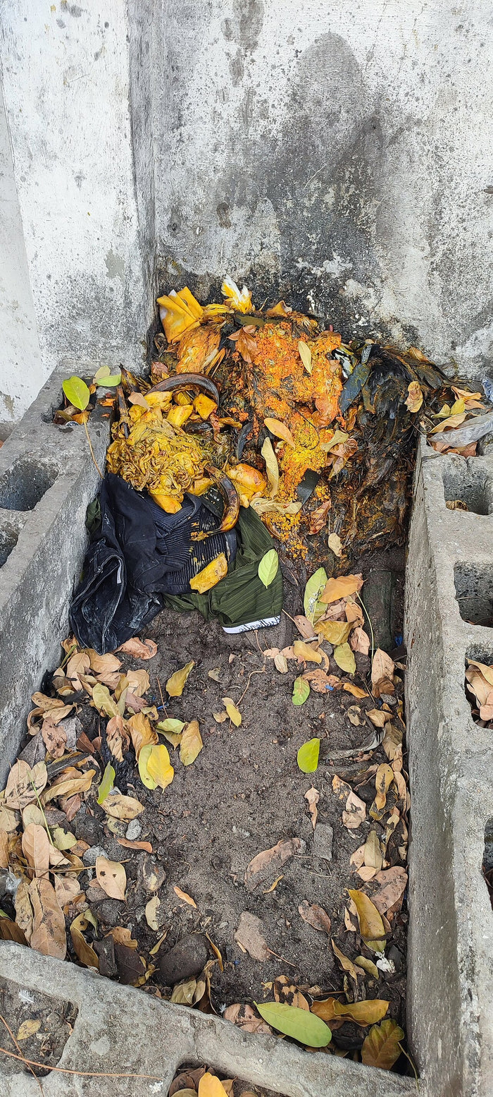 Ogun shrine, 2022: an open concrete shrine with palm-oil offerings and leaves, showing everyday Yoruba worship of Ògún.