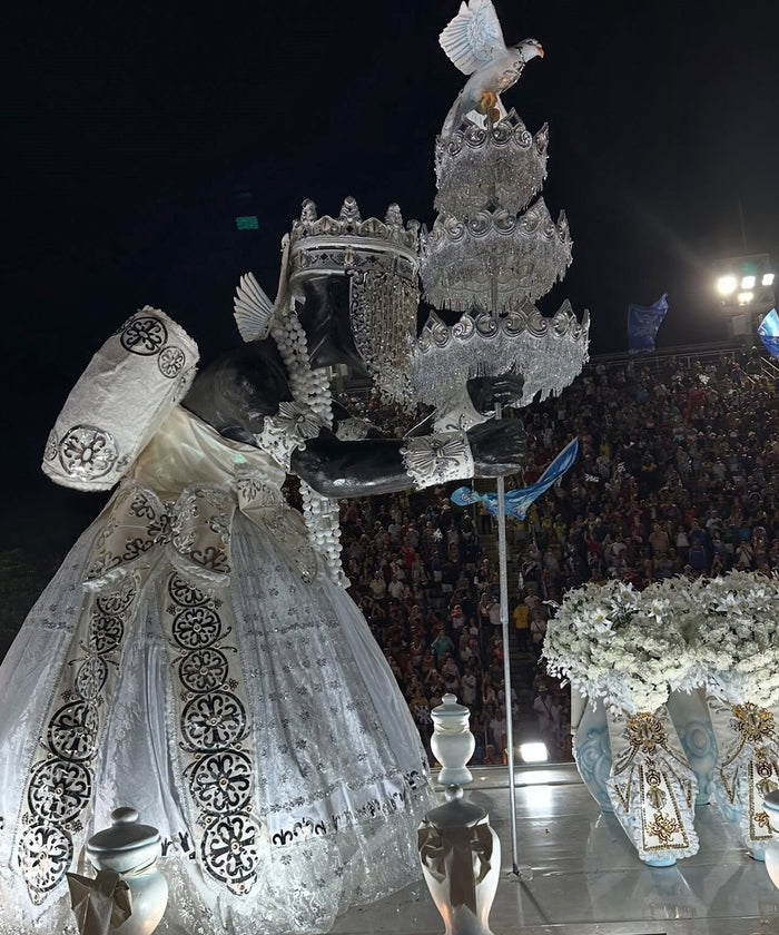Oxalá on a 2025 Beija-flor carnival float, in white and silver with a crown and a dove atop the staff.