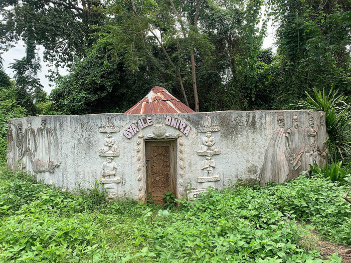 Walled Oya oriri shrine in Oya Grove, with relief carvings and a carved wooden door.