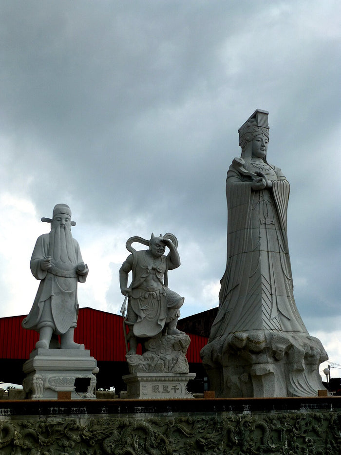 Stone statues at Ping Sien Si: Qianliyan stands beside Mazu, flanked by another attendant figure.