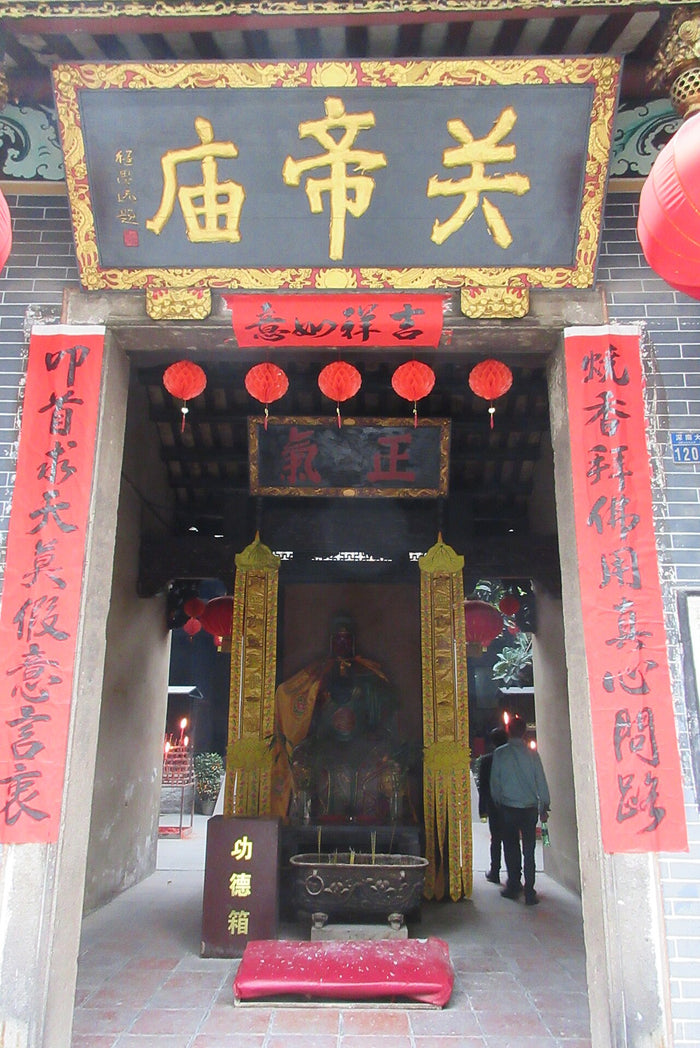 Entrance of a Guandi Temple (關帝廟), with a statue of the deity visible inside and red couplets and lanterns.