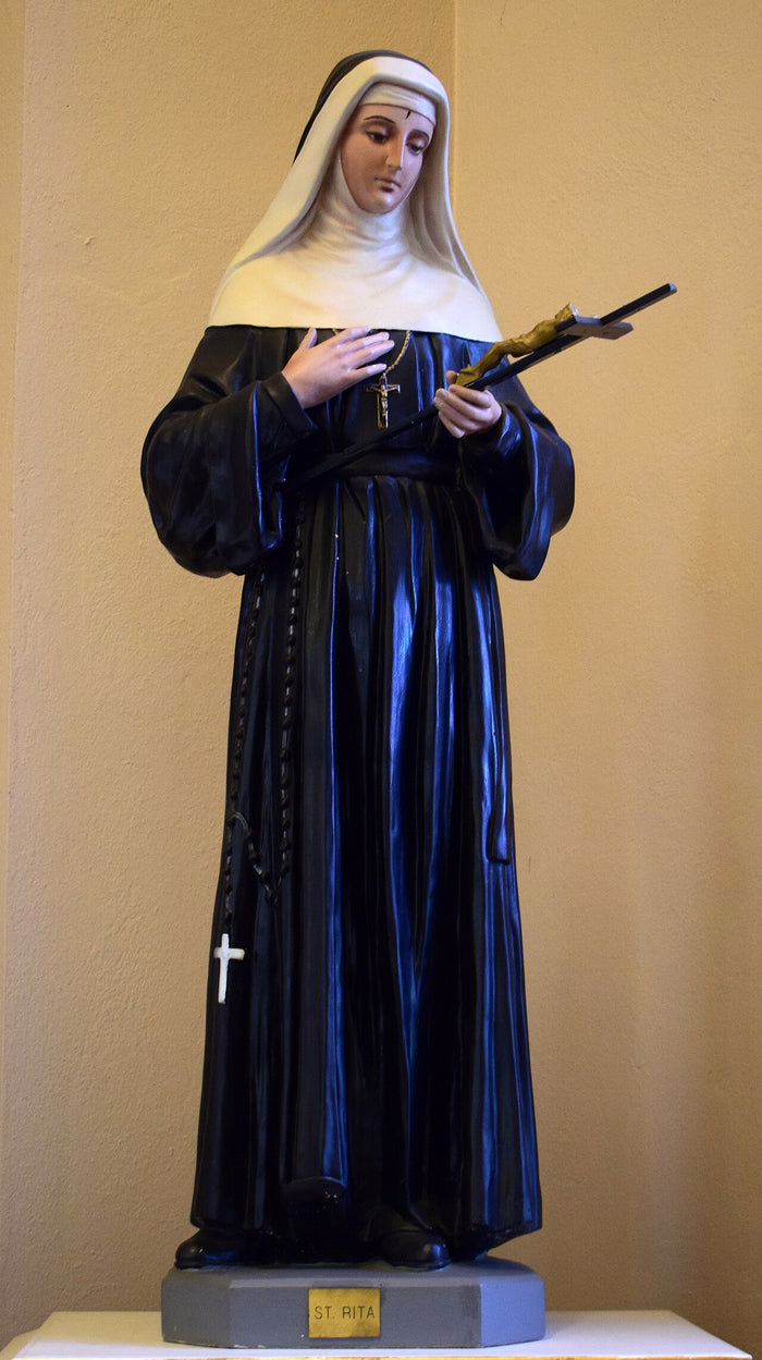 Statue of St Rita in black Augustinian habit with white veil, holding a crucifix, at Sacred Heart Church, New Bavaria, Ohio.