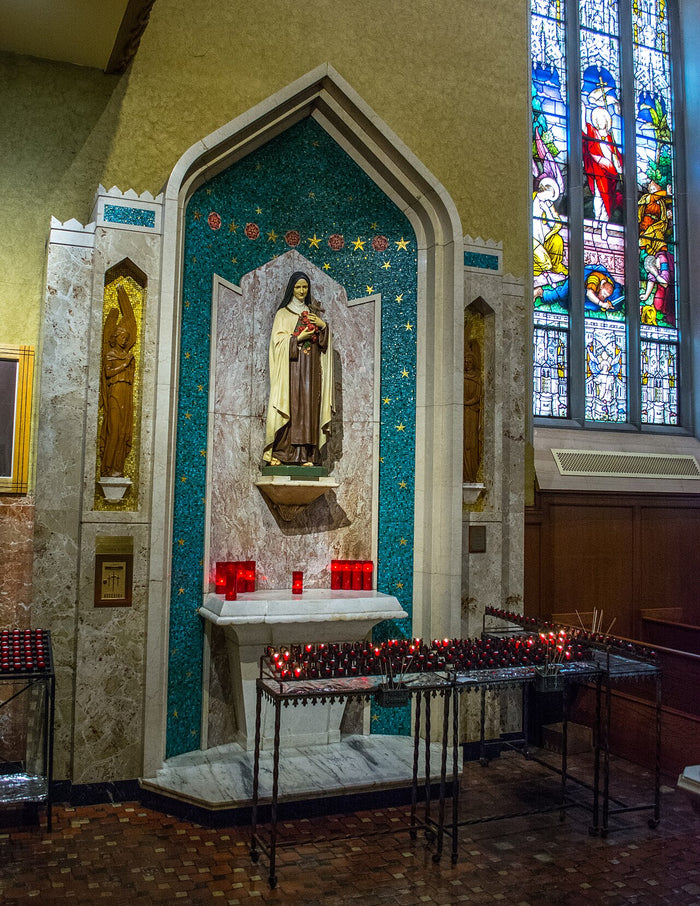 Shrine of Thérèse of Lisieux in St John the Evangelist Cathedral, with her statue, votive candles and stained glass.