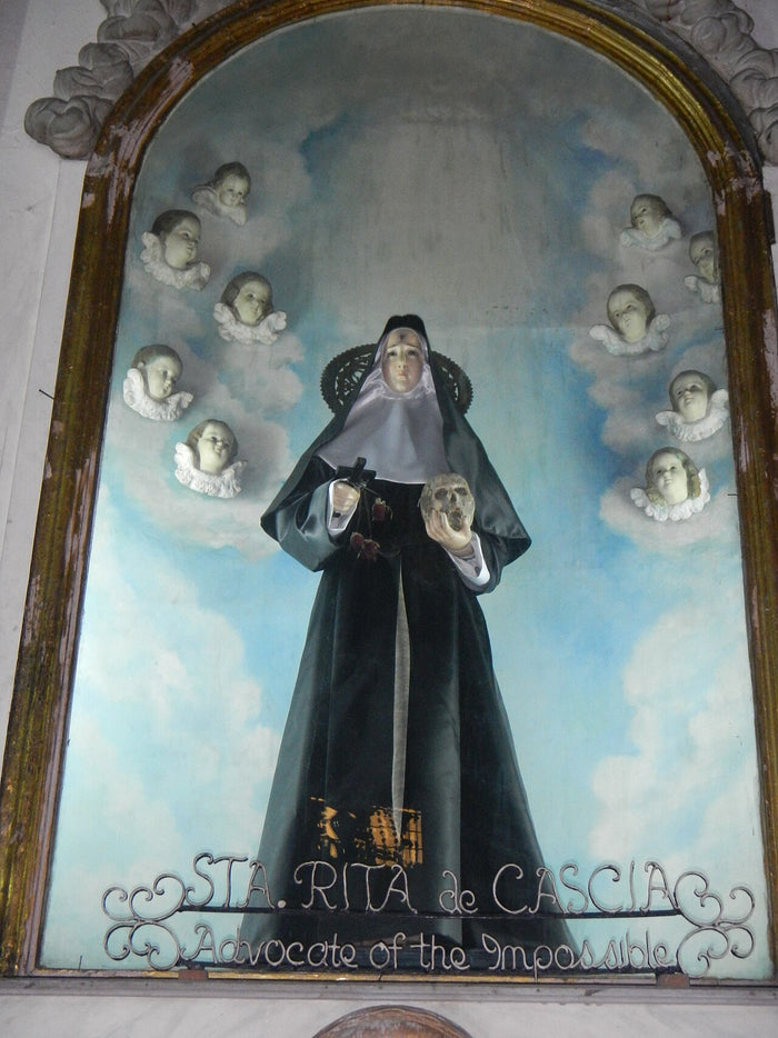 St Rita of Cascia with crucifix and skull, surrounded by cherubs, captioned 'Advocate of the Impossible'; San Agustin Church, Manila.