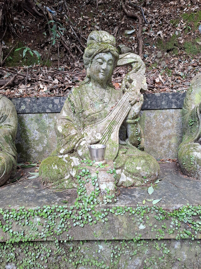 Weathered stone Benzaiten holding a biwa, her main attribute as goddess of music, at Shipporyuji.