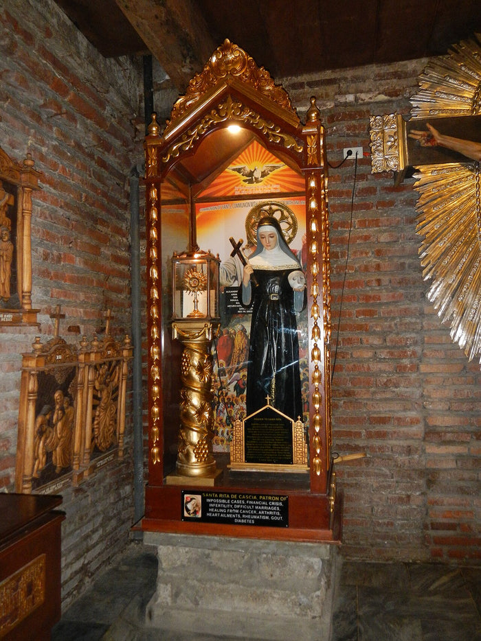 Statue of St Rita in a shrine at Minalin Church, Pampanga, with a plaque listing causes she is invoked for.