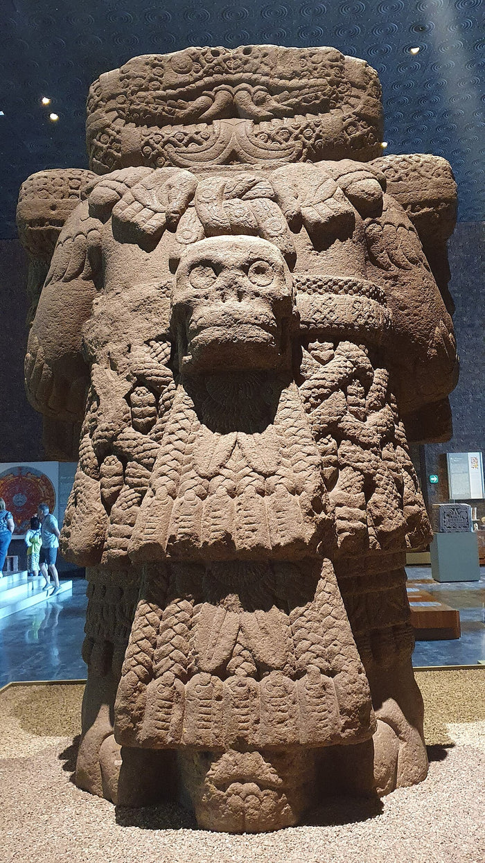 Rear of the Coatlicue statue: a hanging skull pendant, coiled serpents and a layered, feathered skirt show her dual symbolism.