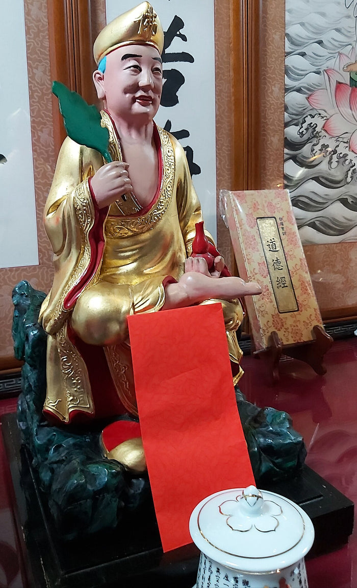 Ji Gong statue in Banqiao, New Taipei, holding a cattail fan and wine gourd, seated casually.