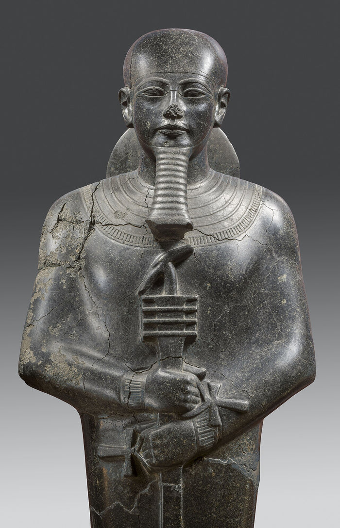 Dark stone statue of Ptah from the New Kingdom (c. 1390–1353 BCE): shrouded, with straight beard, broad collar and was-djed-ankh sceptre.