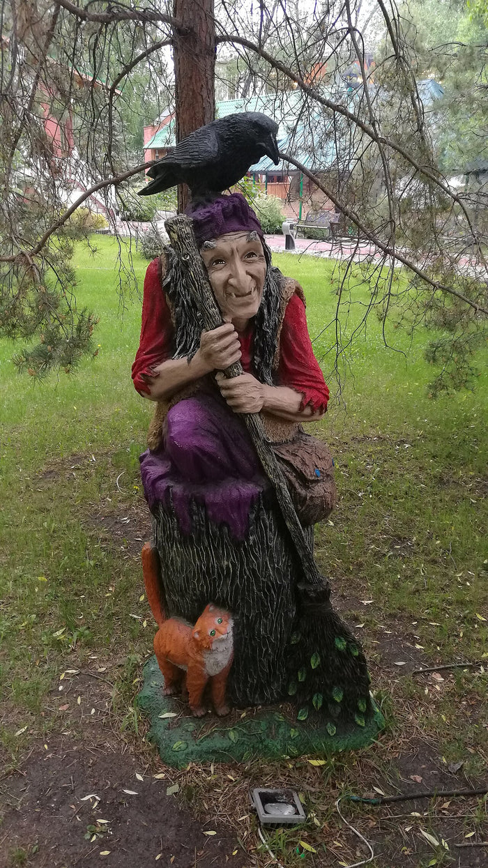 Sculpture of Baba Yaga as an old crone with a broom, a raven and a cat as companions.