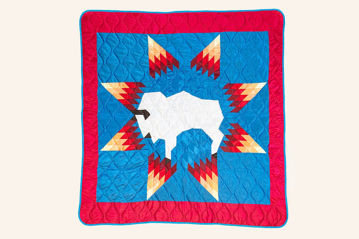 Quilted wall hanging with a white buffalo inside a star pattern, evoking the white buffalo sacred to White Buffalo Calf Woman.