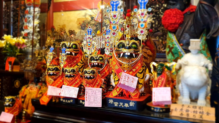 Group of Hu Ye tiger-god statues in red robes on an altar at Xingang Fengtian Temple.