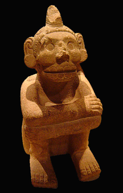 Retouched view of the seated stone Mictlantecuhtli, showing a toothed skull face, crest and crossed arms.