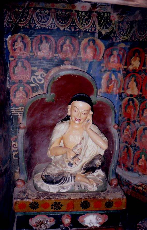 Painted statue in the Pango Chorten, Gyantse (photographed 1993): Milarepa with hand to cheek, set before rows of small painted figures.