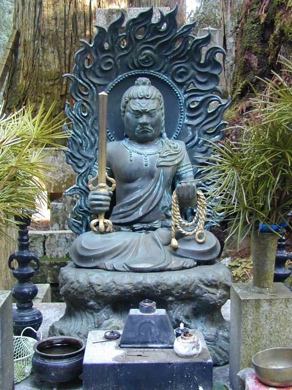 Bronze Fudō Myōō with flame halo, sword and rope at Okunoin cemetery, Kōyasan, a Shingon sacred site.